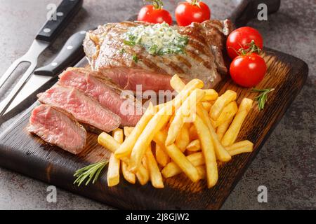 Steak de bœuf grillé moyen avec frites à proximité sur le panneau en bois de la table. Horizontale Banque D'Images