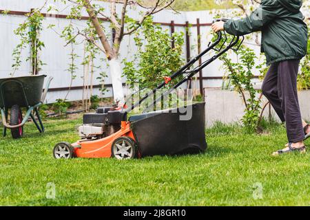 Déplacement de pelouse sur l'herbe verte par beau temps. Déplacement de pelouse sur l'herbe verte dans le jardin moderne. Machine pour couper les pelouses Banque D'Images