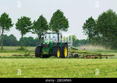 Un tracteur avec faneuse de fourrage en service Banque D'Images