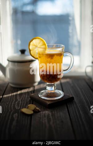 Thé clair ou boisson chaude de l'argousier sur un panneau rustique. Baies et gingembre en verre comme un aliment sain Banque D'Images