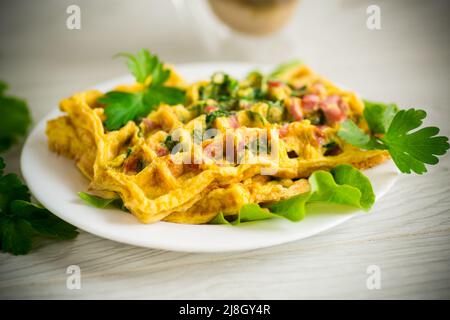 Omelette aux œufs farcie avec des légumes verts et des saucisses frits sous forme de gaufres, sur une table en bois Banque D'Images