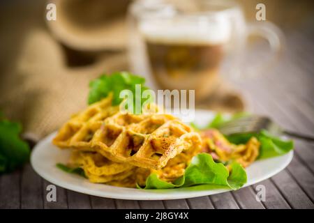Omelette aux œufs farcie avec des légumes verts et des saucisses frits sous forme de gaufres, sur une table en bois Banque D'Images