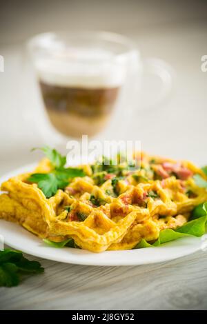 Omelette aux œufs farcie avec des légumes verts et des saucisses frits sous forme de gaufres, sur une table en bois Banque D'Images