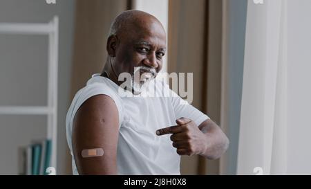 Portrait afro-américain ancien homme mature patient montre le plâtre médical sur la marque d'injection d'épaule satisfait mâle après la vaccination avec le covid Banque D'Images