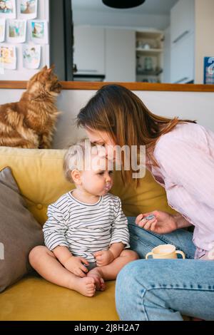 Maman nourrit un petit enfant à la maison avec du yaourt à la cuillère. Concept de famille Banque D'Images