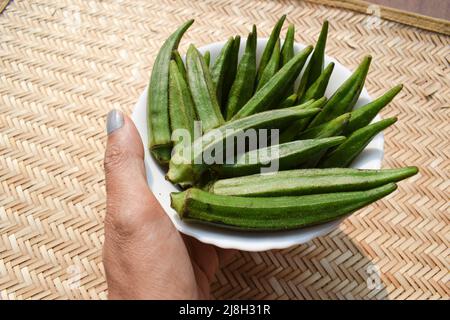 Femelle tenant des légumes frais d'Okra ou des légumes verts doigt de dame ou ladyfingers également connu sous le nom de Bhindi en hindi et en ourdou. Banque D'Images