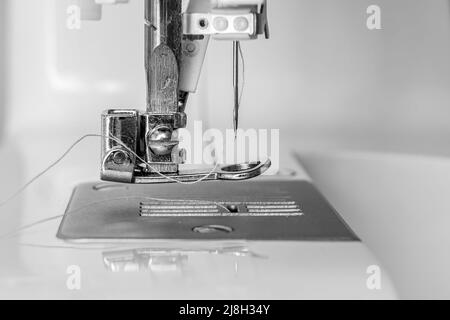 Partie de la machine à coudre gros plan - pied, aiguille et fil. Image monochrome Banque D'Images