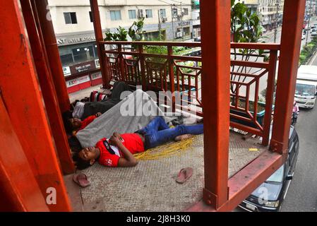 Un groupe d'enfants sans abri dort sur le pont à pied à Dhaka, au Bangladesh, le 16 mai 2022 Banque D'Images