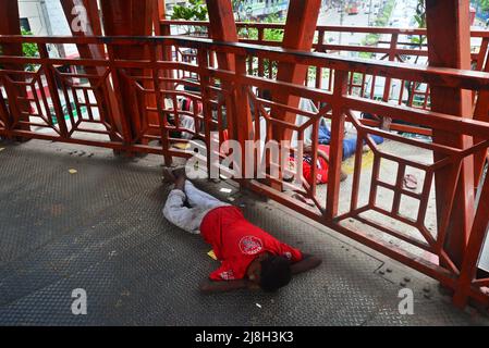 Un groupe d'enfants sans abri dort sur le pont à pied à Dhaka, au Bangladesh, le 16 mai 2022 Banque D'Images