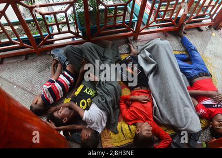 Un groupe d'enfants sans abri dort sur le pont à pied à Dhaka, au Bangladesh, le 16 mai 2022 Banque D'Images