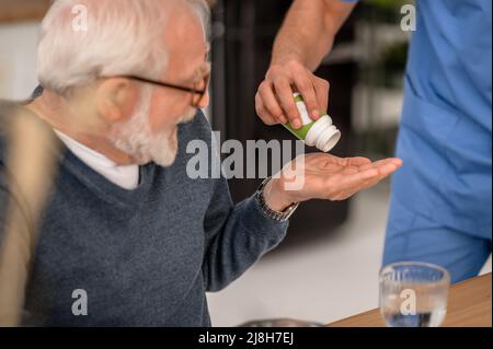 Personne âgée recevant un médicament de la bouteille de pilules Banque D'Images