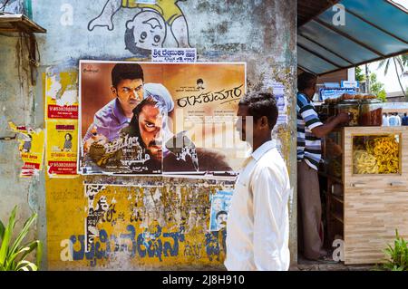 Belur, Karnataka, Inde : Un homme passe devant une affiche de film Bollywood sur un mur. Banque D'Images