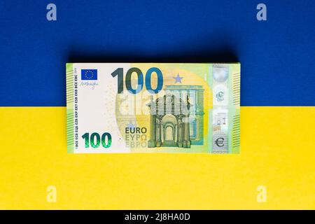 Pile de cent billets en euros sur le drapeau ukrainien. Argent aide de l'Europe à l'Ukraine concept Banque D'Images