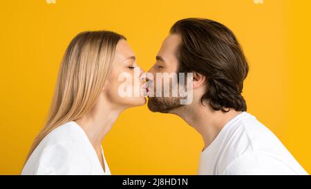 Joyeux millennium européen gars et femme en T-shirts blancs baiser et profiter du moment tendre ensemble Banque D'Images