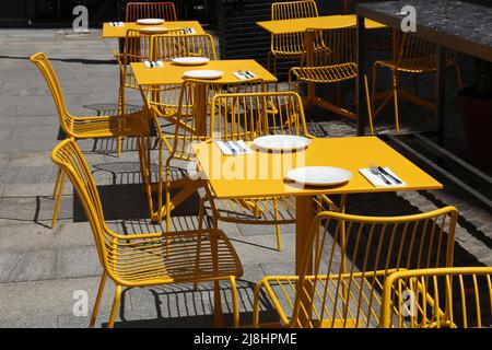 Café-terrasse en Pologne. Varsovie, Pologne. Café hippster moderne avec chaises en acier jaune et table à l'extérieur. Banque D'Images