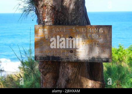 Panneau d'avertissement en bois interdisant la baignade sur la plage de Larson, sur la rive nord de l'île de Kauai, à Hawaï, aux États-Unis Banque D'Images