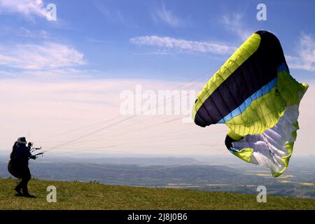 Kozakov, République tchèque. 16th mai 2022. Un parapente se prépare à partir d'un Kozakov (à 100 kilomètres au nord de Prague) pendant une journée ensoleillée dans le Paradis tchèque. Le parapente est un sport de vol de loisir et de compétition. Le pilote est assis dans un harnais suspendu sous une aile en tissu, dont la forme est formée par la pression de l'air entrant dans les évents à l'avant de l'aile. (Credit image: © Slavek Ruta/ZUMA Press Wire) Banque D'Images