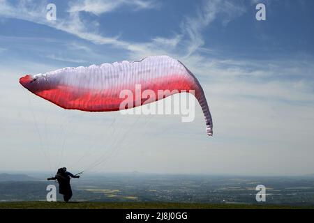 Kozakov, République tchèque. 16th mai 2022. Un parapente se prépare à partir d'un Kozakov (à 100 kilomètres au nord de Prague) pendant une journée ensoleillée dans le Paradis tchèque. Le parapente est un sport de vol de loisir et de compétition. Le pilote est assis dans un harnais suspendu sous une aile en tissu, dont la forme est formée par la pression de l'air entrant dans les évents à l'avant de l'aile. (Credit image: © Slavek Ruta/ZUMA Press Wire) Banque D'Images