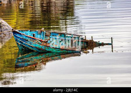 Bateau de pêche naufragé sur le Loch Carron avec une vue imprenable sur le village pittoresque de Plockton, le joyau des Highlands, en Écosse Banque D'Images