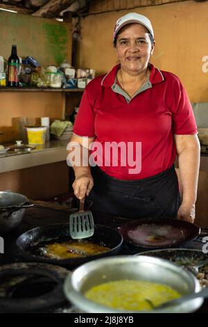 Femme regardant la caméra tout en cuisinant un repas typique du Costa Rica. Banque D'Images