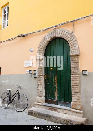 Portes vertes et vélo à la porte extérieure de l'Anfiteatro Bed & Breakfast, dans une rue piétonne de Lucca, Toscane, Italie. Banque D'Images