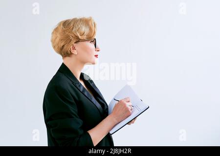 Mature belle femme d'affaires faisant des plans et des notes sur fond blanc. Éducation, affaires, concept de gestion Banque D'Images