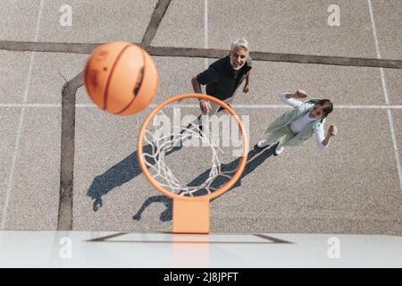 Père heureux et fille de l'adolescence embrassant et se tenant sous un filet de basket-ball, directement au-dessus Banque D'Images