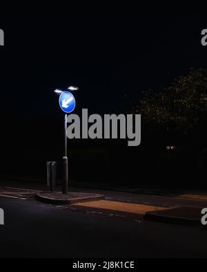 Photo verticale du panneau « Keep Left » de la route britannique la nuit avec un éclairage artificiel contrasté Banque D'Images