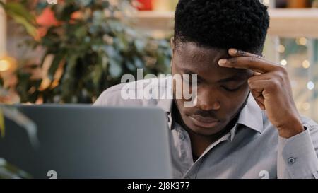 Un jeune homme d'affaires en gros plan regardant l'écran d'ordinateur portable recevant un e-mail lisant des mauvaises nouvelles choquantes surpris choqué par les informations le tenant Banque D'Images