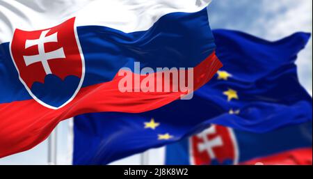 Détail du drapeau national de la Slovaquie qui agite dans le vent avec un drapeau flou de l'Union européenne en arrière-plan par temps clair. Démocratie et politique. Banque D'Images