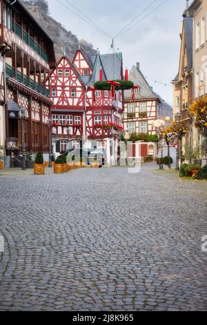 Rue pavée avec une couronne de Noël accrochée à Bacharach, Allemagne menant à la vieille maison, Altes Haus, un bâtiment historique. Banque D'Images