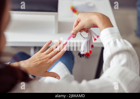 Femme élégante qui choisit la couleur polish en salon Banque D'Images