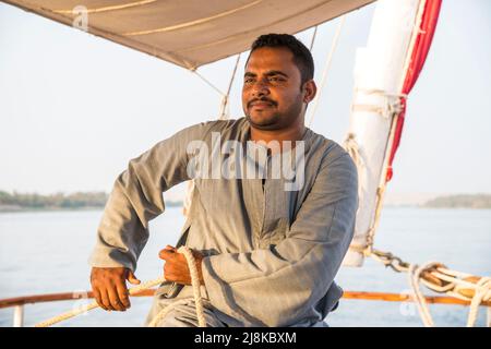 Membre de l'équipage tailler les voiles vêtues de vêtements traditionnels sur un bateau Dahabiya du Nil Banque D'Images