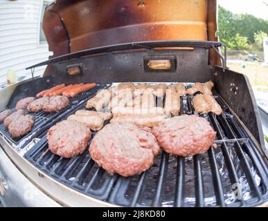 Griller des hamburgers et des chiens sur un gril à gaz par beau temps en été Banque D'Images