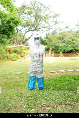 Femme asiatique médecin portant un vêtement de protection individuelle et un masque facial dans le jardin à l'extérieur de l'après-midi. Banque D'Images