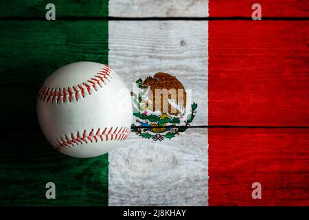 Base-ball en cuir sur fond de bois rustique peint avec un drapeau mexicain avec espace de copie. Le Mexique est l'un des plus grands pays de baseball au monde. Banque D'Images