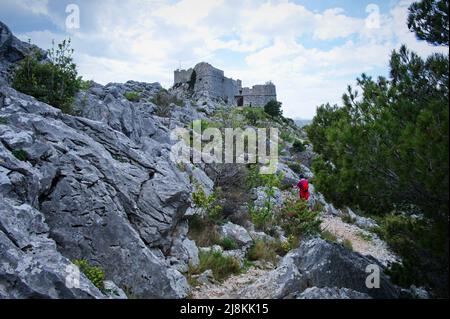 Femme randonnée près de la forteresse médiévale sur le sommet de la montagne rocheuse Banque D'Images