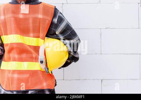 Vue arrière de l'ingénieur, de l'architecte, du superviseur travailleur porter des vêtements réfléchissants pour la sécurité de l'opération de travail tenir le casque de sécurité dans la veste debout Banque D'Images