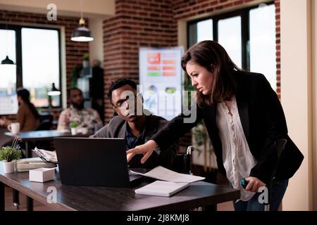 Paralysé travailleur de l'entreprise et jeune femme faisant le travail d'équipe dans un bureau pour personnes handicapées. Hommes d'affaires travaillant sur le projet, employé qui s'occupe de déficience physique chronique en fauteuil roulant. Banque D'Images