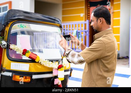 Chauffeur occupé à prendre la photo de son nouvel auto Rickshaw avant de conduire pour poster sur les médias sociaux - concept de démarrage de nouvelles petites entreprises, le transport Banque D'Images