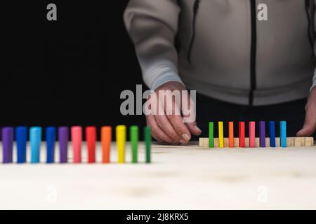 Photo conceptuelle des mains préparant une rangée de pierres domino. Effet Domino avec pierres colorées et espace de copie Banque D'Images