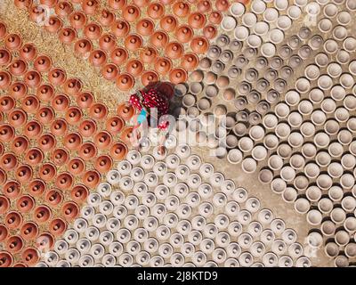 17 mai 2022, Brahmanbaria, Chittagong, Bangladesh : une femme arrange des milliers de pots d'argile avant d'être transportée pour vendre sur un marché à Brahmanbaria, Bangladesh. Les pots d'argile sont disposés à sécher sous le soleil brûlant avant qu'ils soient chargés dans des fours pour tirer comme une forme d'affaires de poterie. Environ 3 000 pots d'argile sont faits ici sur une base quotidienne et chacun d'eux est vendu pour 2 dollars (2$). La poterie, un commerce ancien, n'est faite que par les gens de la communauté ''Pal'' (Communauté Potters) de l'hindouisme. Pendant des siècles, ils ont vécu leurs compétences en poterie. Même aujourd'hui, leurs pots sont de Banque D'Images