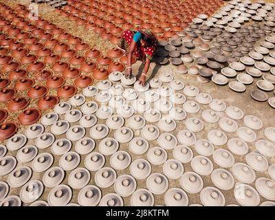 17 mai 2022, Brahmanbaria, Chittagong, Bangladesh : une femme arrange des milliers de pots d'argile avant d'être transportée pour vendre sur un marché à Brahmanbaria, Bangladesh. Les pots d'argile sont disposés à sécher sous le soleil brûlant avant qu'ils soient chargés dans des fours pour tirer comme une forme d'affaires de poterie. Environ 3 000 pots d'argile sont faits ici sur une base quotidienne et chacun d'eux est vendu pour 2 dollars (2$). La poterie, un commerce ancien, n'est faite que par les gens de la communauté ''Pal'' (Communauté Potters) de l'hindouisme. Pendant des siècles, ils ont vécu leurs compétences en poterie. Même aujourd'hui, leurs pots sont de Banque D'Images