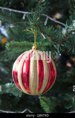 Une boule rouge avec des rayures jaunes sur l'arbre du nouvel an Banque D'Images