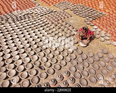 17 mai 2022, Brahmanbaria, Chittagong, Bangladesh : une femme fabrique des pots d'argile à vendre sur un marché de Brahmanbaria, Bangladesh. Les pots d'argile sont disposés à sécher sous le soleil brûlant avant qu'ils soient chargés dans des fours pour tirer comme une forme d'affaires de poterie. Environ 3 000 pots d'argile sont faits ici sur une base quotidienne et chacun d'eux est vendu pour 2 dollars (2$). La poterie, un commerce ancien, n'est faite que par les gens de la communauté ''Pal'' (Communauté Potters) de l'hindouisme. Pendant des siècles, ils ont vécu leurs compétences en poterie. Même aujourd'hui, leurs pots sont très demandés dans tout le Bangladesh. Le Banque D'Images