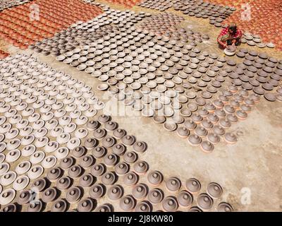 17 mai 2022, Brahmanbaria, Chittagong, Bangladesh : une femme fabrique des pots d'argile à vendre sur un marché de Brahmanbaria, Bangladesh. Les pots d'argile sont disposés à sécher sous le soleil brûlant avant qu'ils soient chargés dans des fours pour tirer comme une forme d'affaires de poterie. Environ 3 000 pots d'argile sont faits ici sur une base quotidienne et chacun d'eux est vendu pour 2 dollars (2$). La poterie, un commerce ancien, n'est faite que par les gens de la communauté ''Pal'' (Communauté Potters) de l'hindouisme. Pendant des siècles, ils ont vécu leurs compétences en poterie. Même aujourd'hui, leurs pots sont très demandés dans tout le Bangladesh. Le Banque D'Images