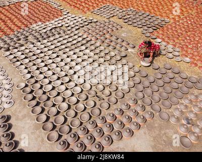 17 mai 2022, Brahmanbaria, Chittagong, Bangladesh : une femme fabrique des pots d'argile à vendre sur un marché de Brahmanbaria, Bangladesh. Les pots d'argile sont disposés à sécher sous le soleil brûlant avant qu'ils soient chargés dans des fours pour tirer comme une forme d'affaires de poterie. Environ 3 000 pots d'argile sont faits ici sur une base quotidienne et chacun d'eux est vendu pour 2 dollars (2$). La poterie, un commerce ancien, n'est faite que par les gens de la communauté ''Pal'' (Communauté Potters) de l'hindouisme. Pendant des siècles, ils ont vécu leurs compétences en poterie. Même aujourd'hui, leurs pots sont très demandés dans tout le Bangladesh. Le Banque D'Images