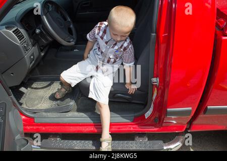 l'enfant sort de la voiture rouge dans la rue Banque D'Images