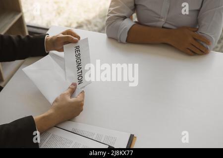 Une femme prend la poignée à l'enveloppe de démission tout en étant remise à la femme gestionnaire. Banque D'Images