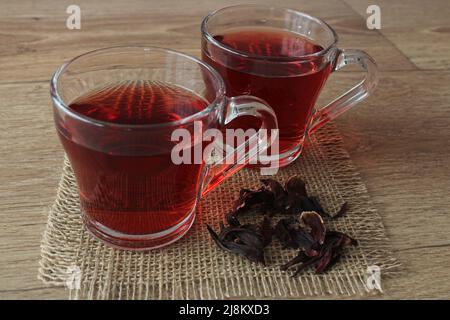 Hibiscus (rose de Chine) ou thé rouge chaud en verre sur la table de cuisine. Banque D'Images